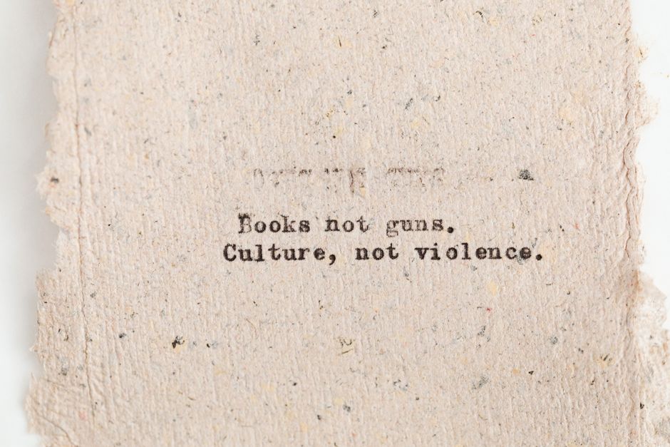 Close-up of typewritten text promoting books over guns and culture over violence.